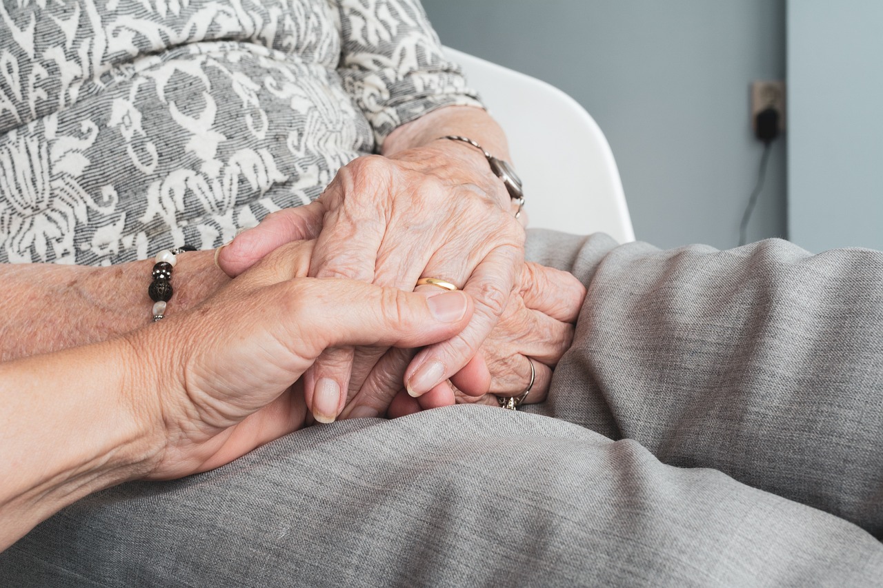 younger hands holding older hands to support dementia patient